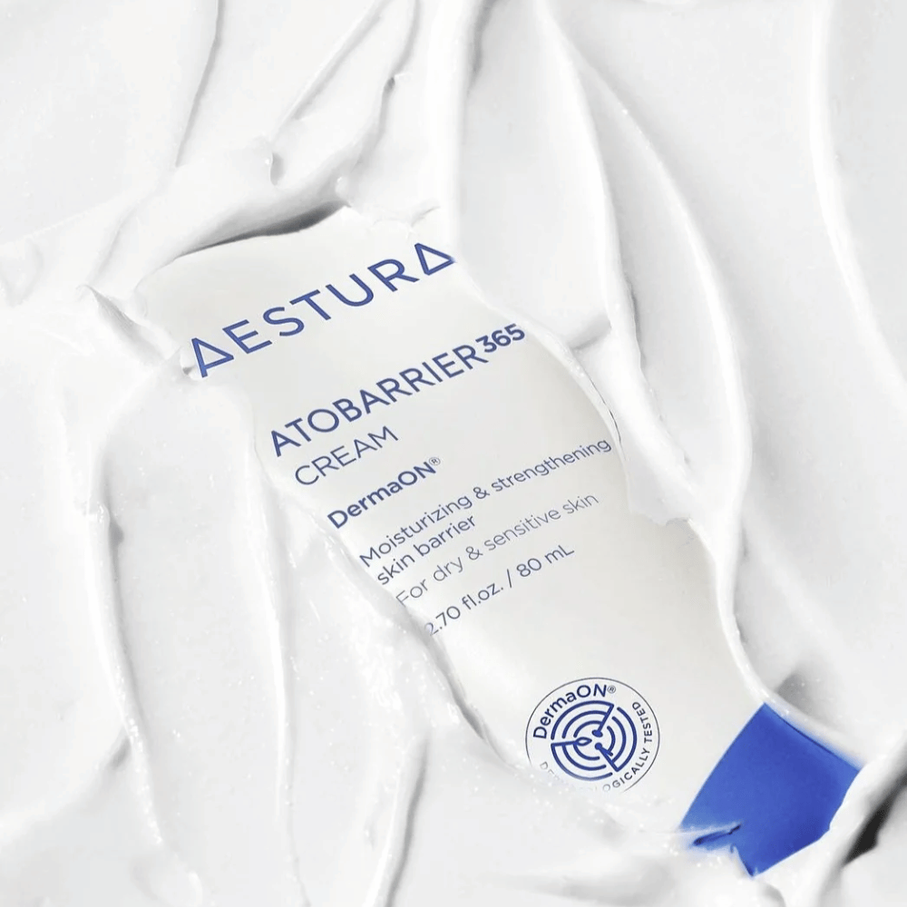 Aestura Atobarrier 365 Cream är perfekt för torr och känslig hud. Med DermaON™ teknologi, återfuktar och stärker denna kräm hudbarriären. Produkten visas här i en 80 ml tub, delvis täckt av sin egen krämiga konsistens, vilket framhäver dess rika, återfuktande egenskaper.